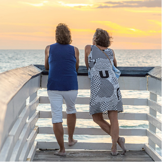 Two woman looking out at a beach sunset over the water