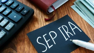 A book, calculator, and black note with 'SEP IRA' written on it sitting on table