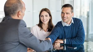 Man shaking hands with a financial advisor with his wife sitting next to him