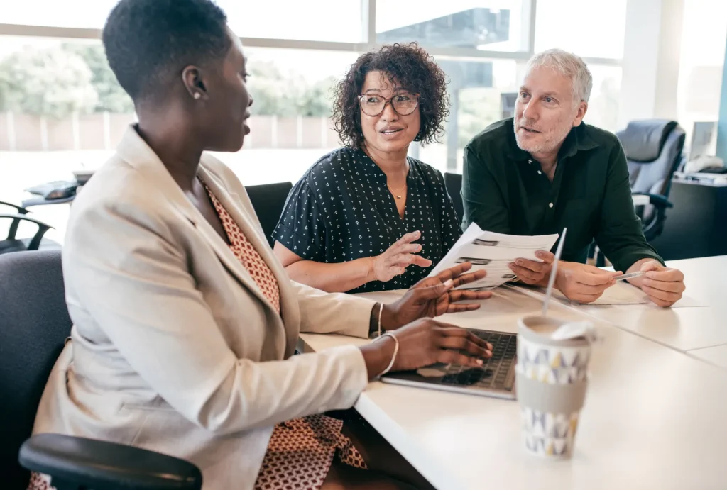 Married couple sitting down with financial advisor in an office space to discuss healthcare costs in retirement