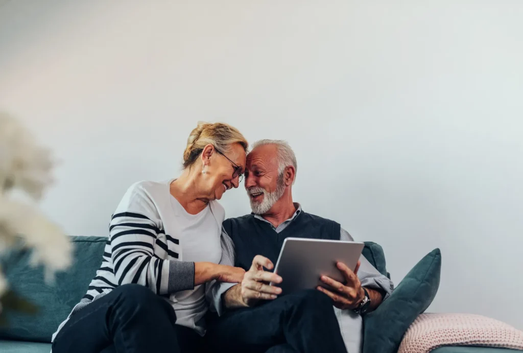 older couple sitting on couch with tablet preparing for healthcare costs in retirement