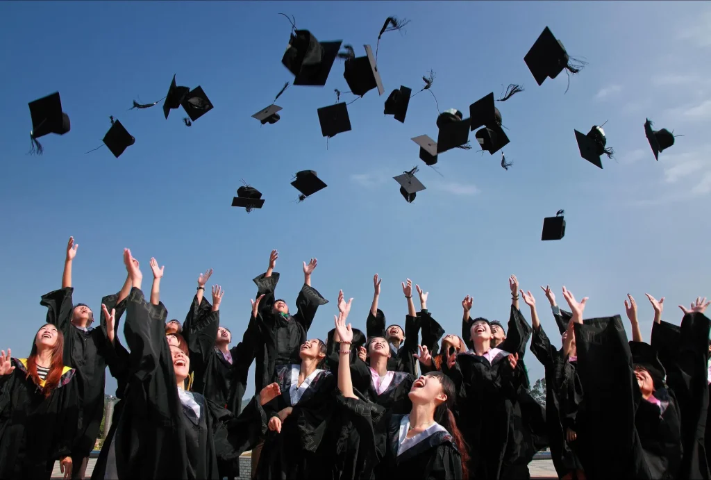 Graduating college seniors throwing grad caps in the air