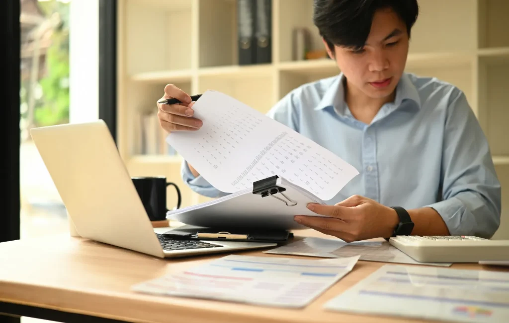 man sitting at a desk with a laptop looking at financial documents to create a bubdget